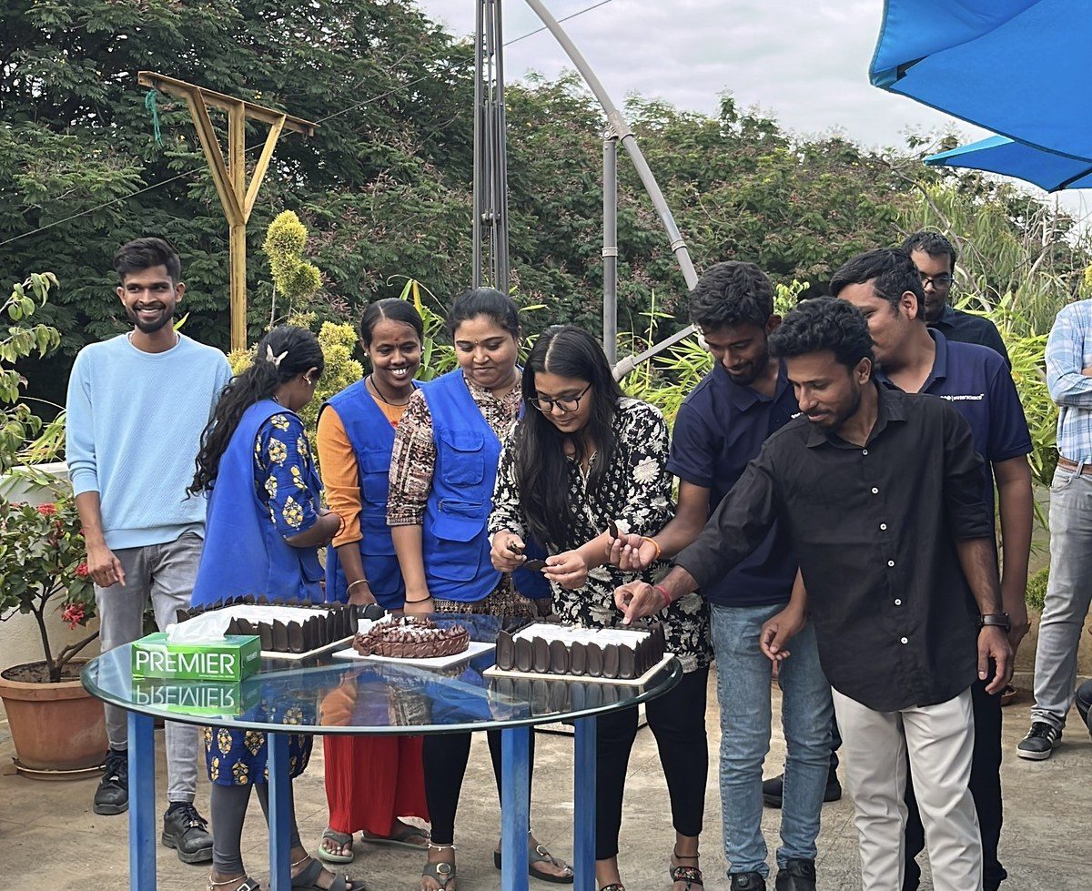 Team cutting cakes together at an outdoor celebration